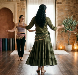 Profesora de danza oriental liderando una clase de bienestar frente a alumnas, mostrando el contraste entre el baile y el gimnasio con Emperatriz Bellydance.